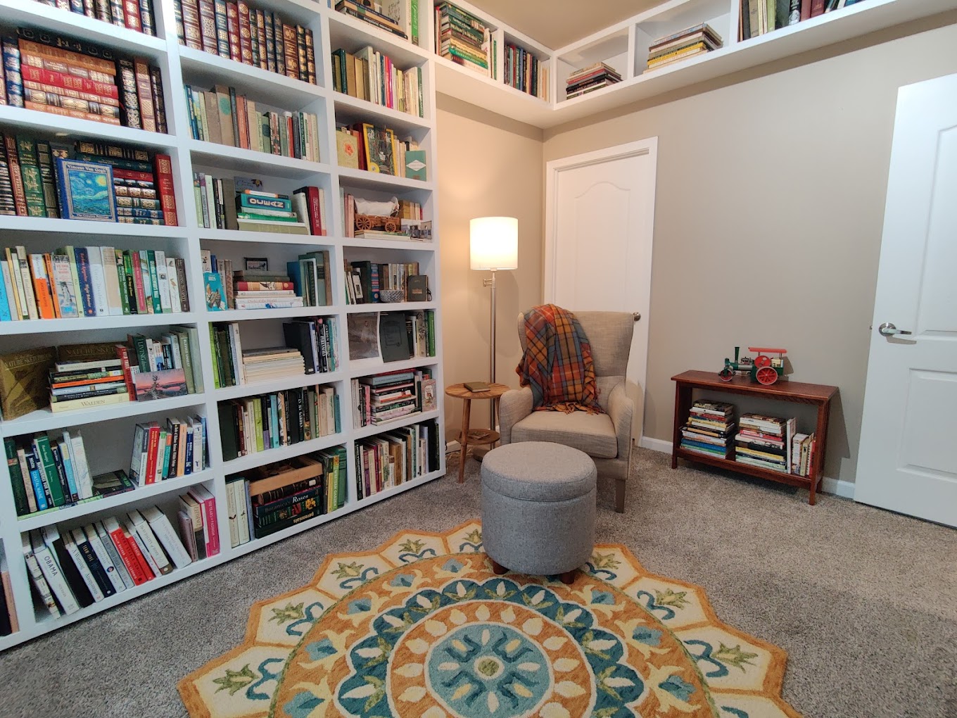 Home library with white shelving around a reading area